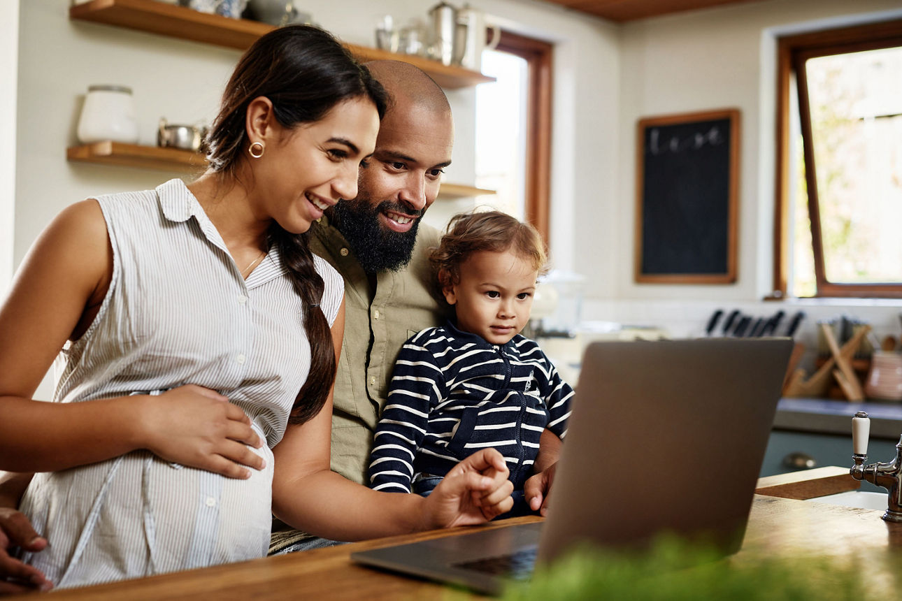 Eine junge Familie beantragt am Laptop Kindergeld.