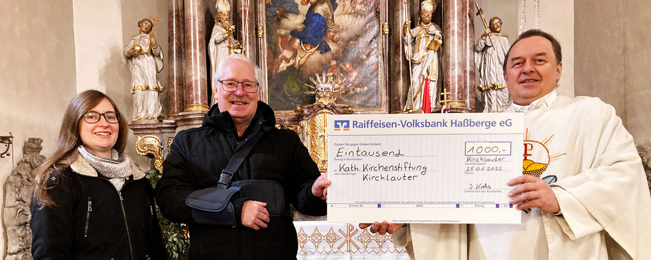 Johanna Krebs von der Raiffeisen-Volksbank Haßberge eG übergibt einen Spendenscheck an die Kath. Kirchenstiftung Kirchlauter