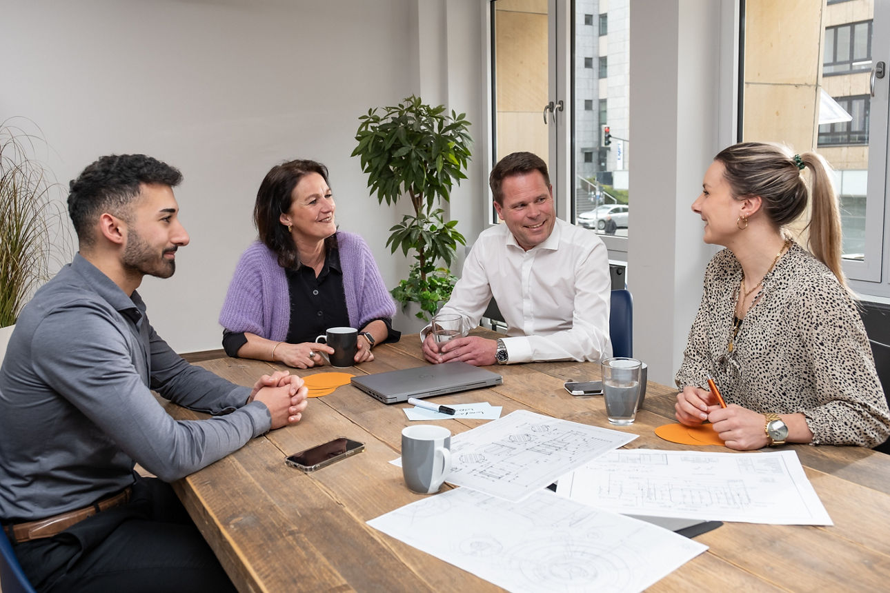 Eine Gruppe sitzt an einem Tisch und lächelt sich an