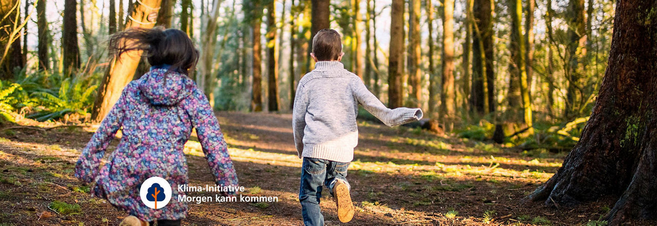 Zwei Kinder rennen auf einem Waldweg