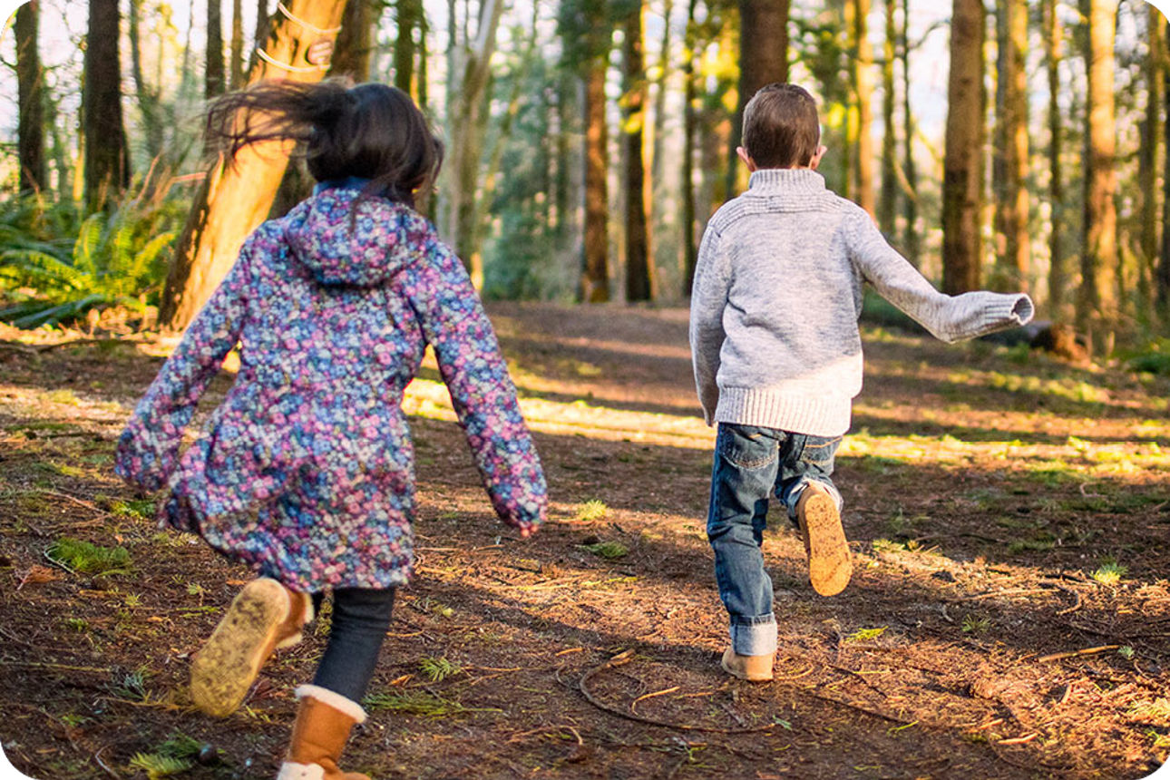 Zwei Kinder laufen durch einen Wald