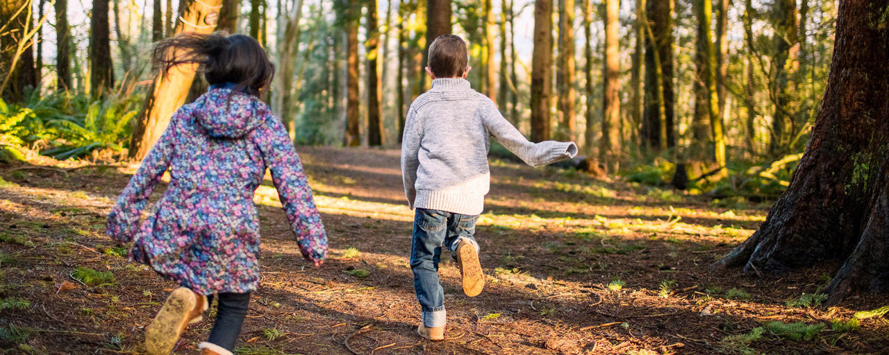 Zwei Kinder laufen durch einen Wald