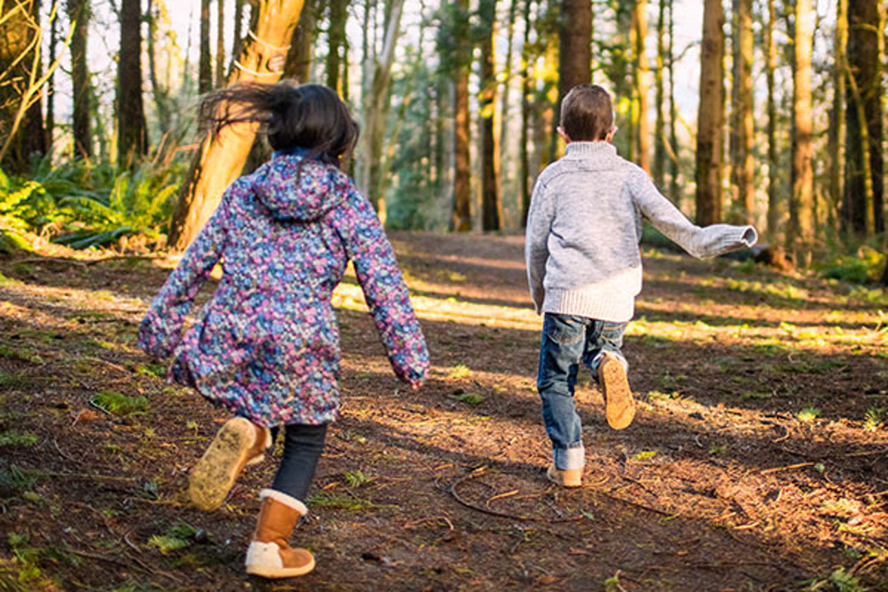 Zwei Kinder laufen durch einen Wald
