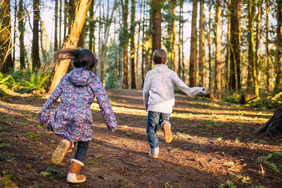 Zwei Kinder laufen durch einen Wald
