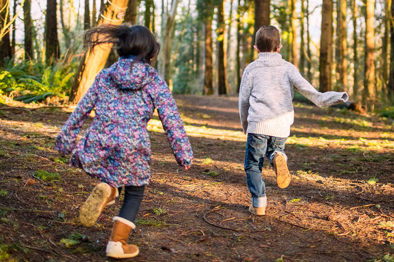 Zwei Kinder laufen durch einen Wald