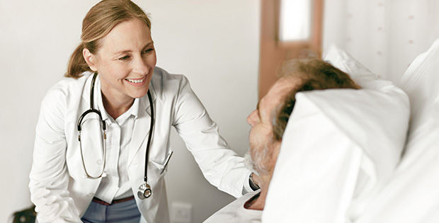 Eine Ärztin beugt sich freundlich lächelnd zu Ihrem Patienten