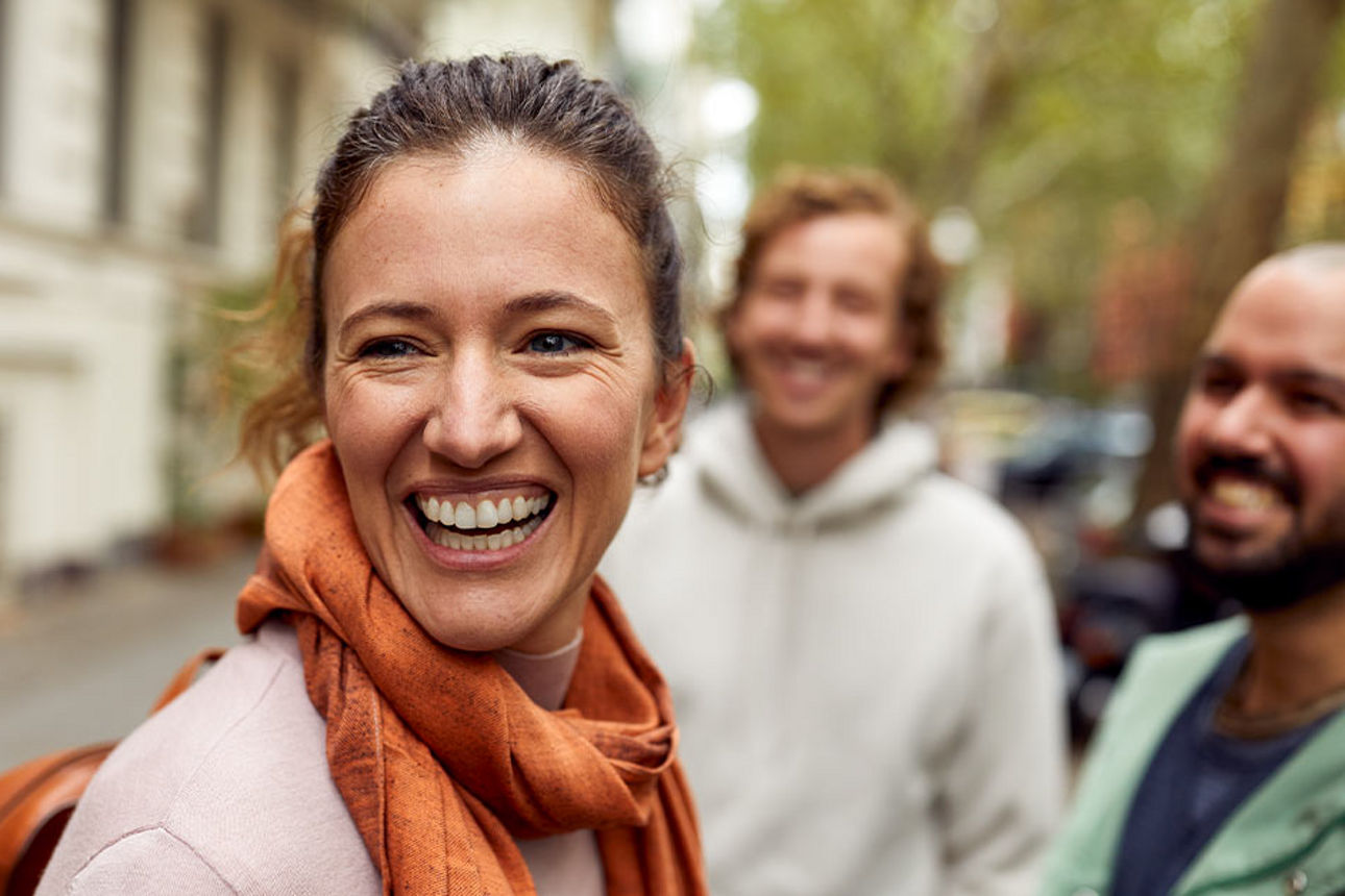 Eine Frau steht in einer kleinen Gruppe zusammen und lächelt.