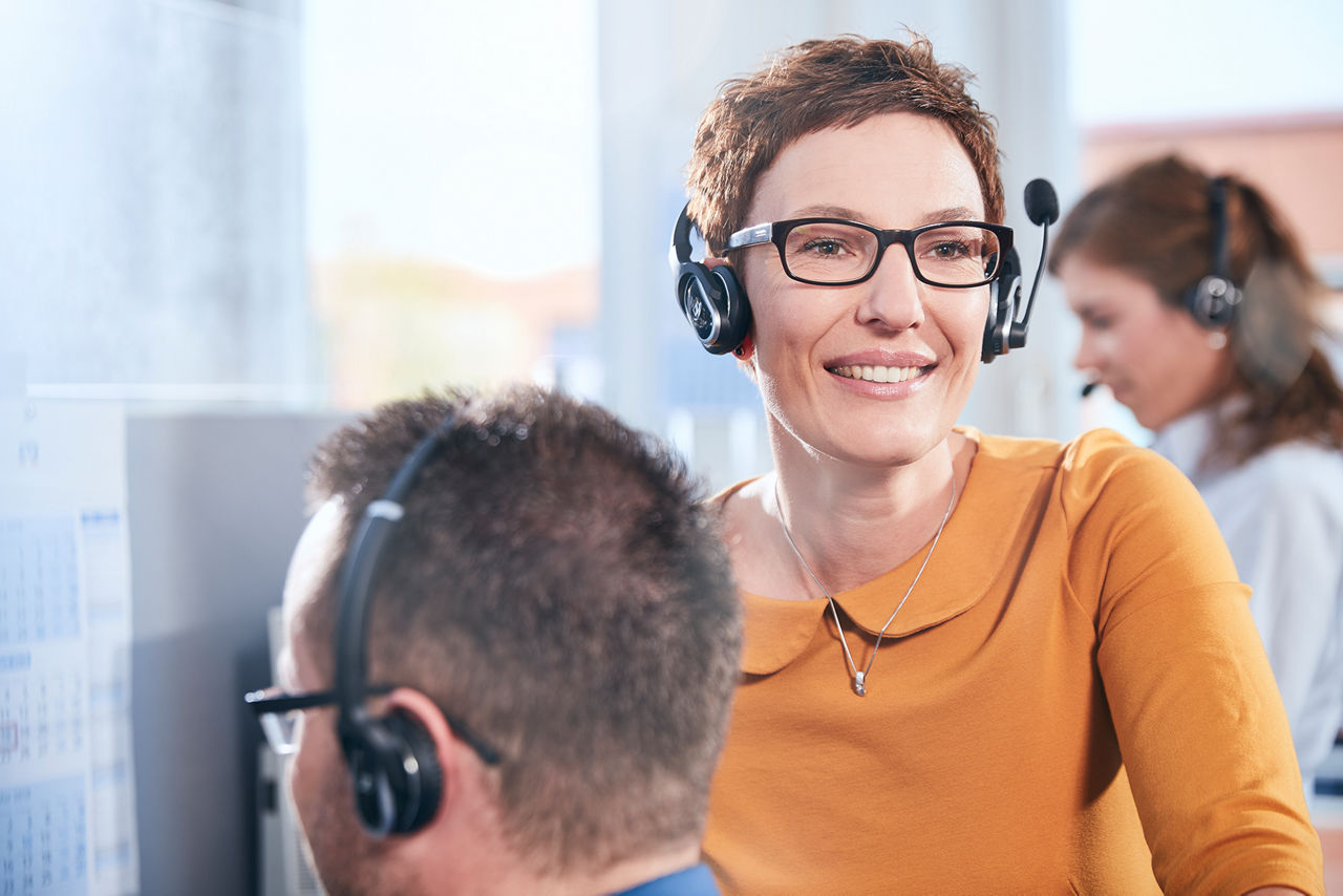 Eine Frau mit einem Headset lächelt in die Kamera