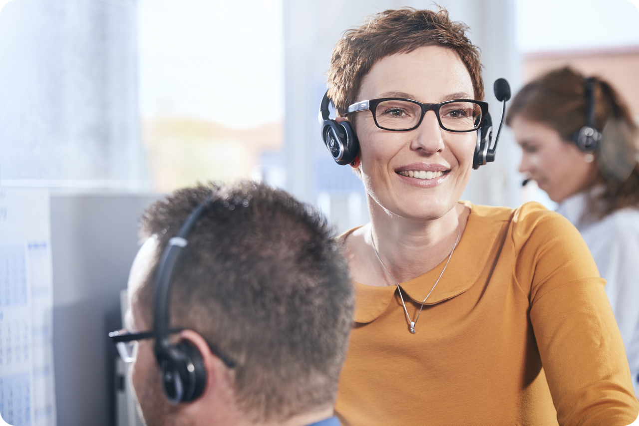 Eine Frau mit einem Headset lächelt in die Kamera