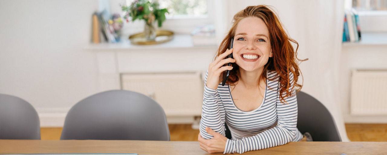 Glückliche Frau am Handy mit der Service-Hotline