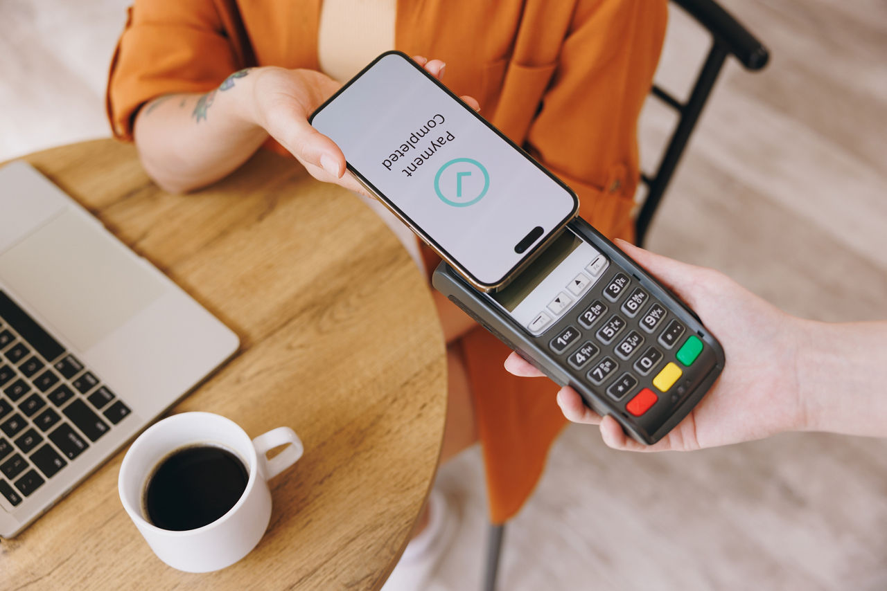 Frau zahlt per Android Digitales Bezahlen ihren Kaffee