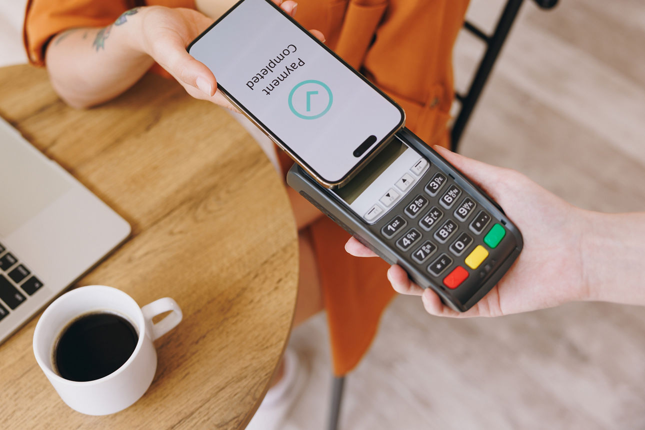 Frau zahlt per Android Digitales Bezahlen ihren Kaffee