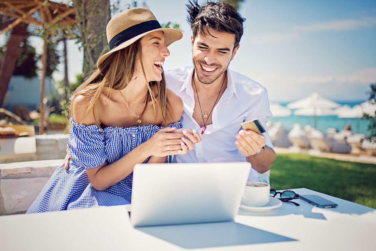 Junges Paar nutzt OnlineBanking in der Strandbar
