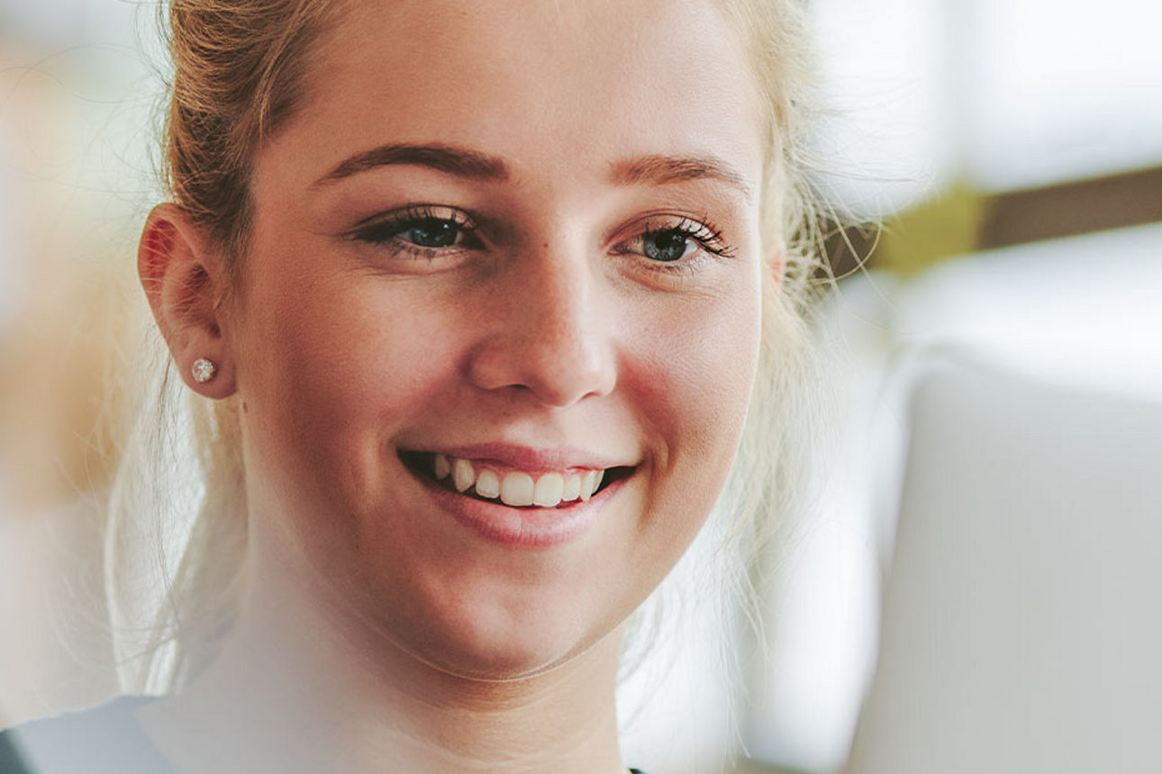 Eine lächelnde Frau, die an einem Laptop arbeitet