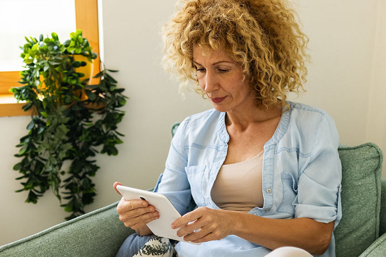 Frau mit Locken auf dem Sessel mit Tablet