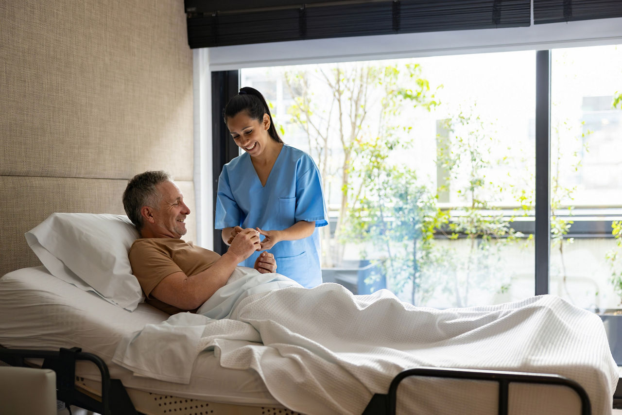 Ein Mann liegt in einem modernen Krankenzimmer und wird von einer Krankenschwester versorgt.