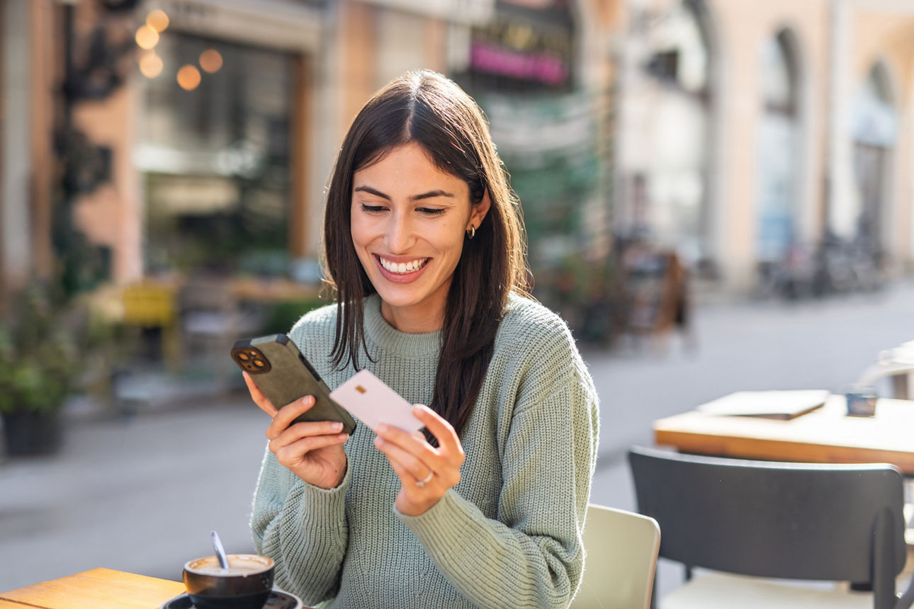 Frau zeigt goldfarbene Kreditkarte vor die Kamera