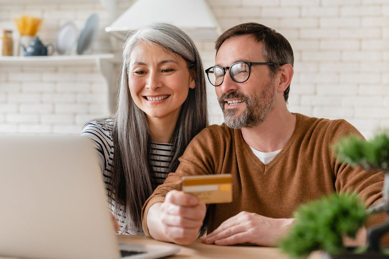 Ein Paar blickt gemeinsam auf einen Bildschirm und freuen sich. 