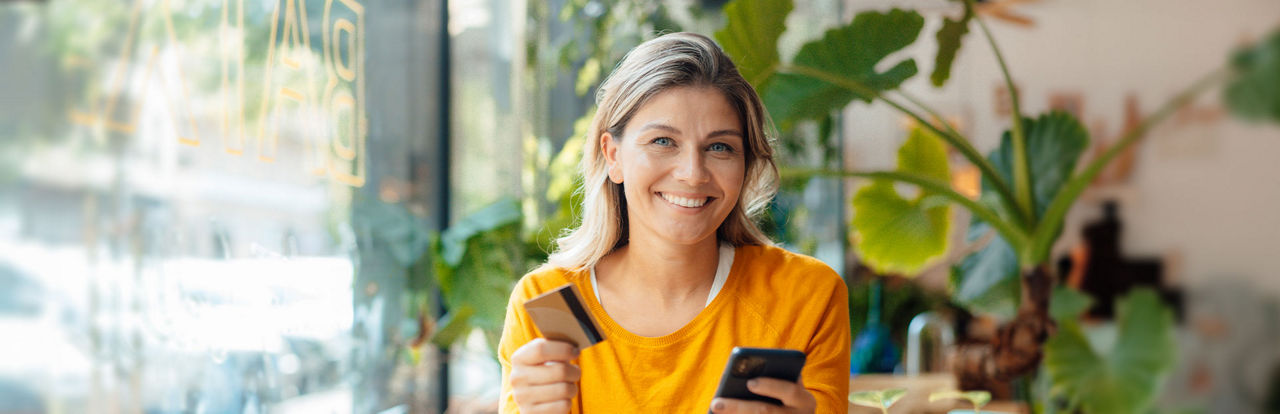 Frau hält Smartphone und Kreditkarte in der Hand