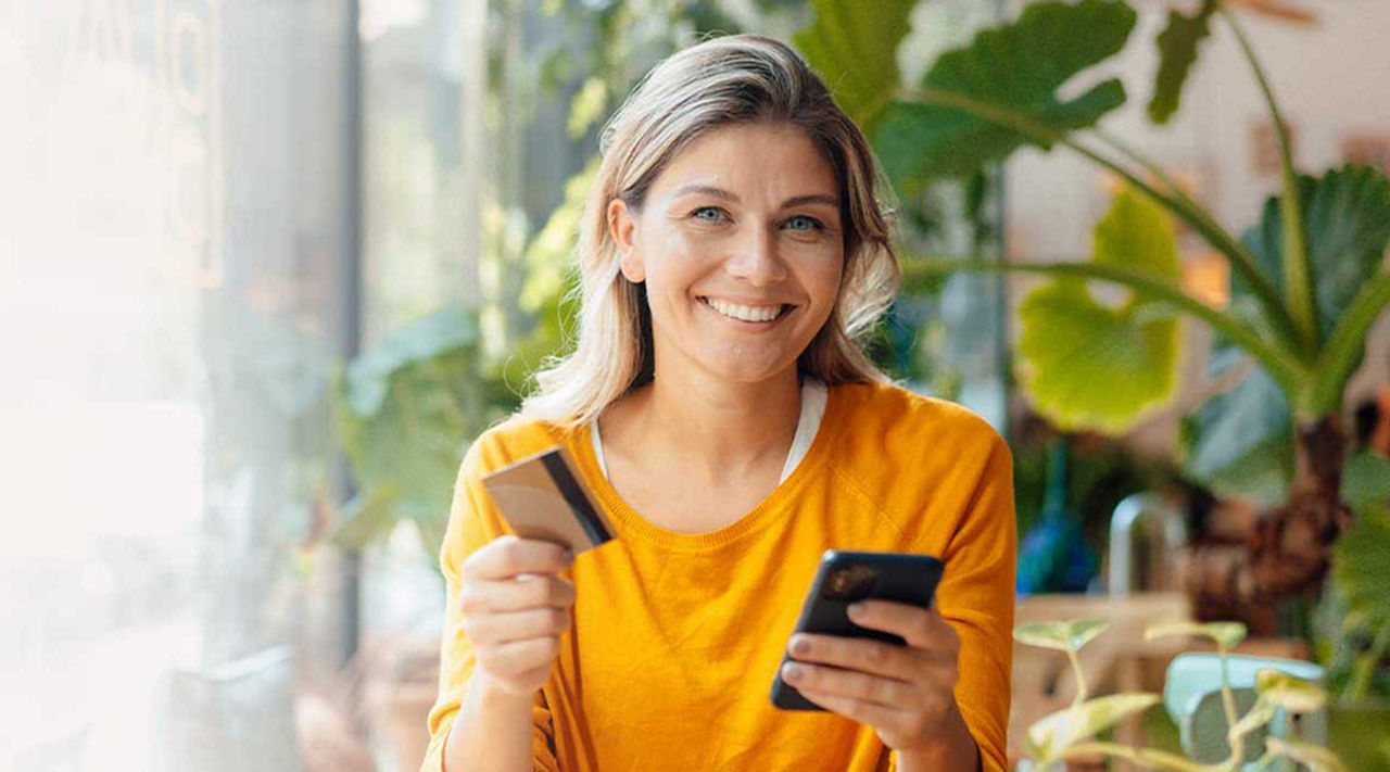 Die EDEKA-Mastercard® Classic steht angelehnt an einem Pappbecher
