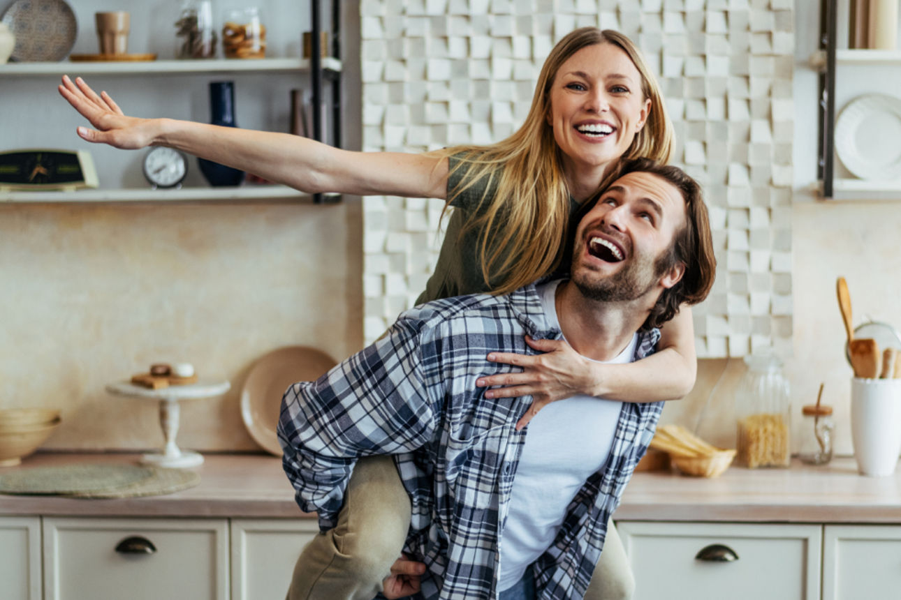 Ein Mann trägt eine Frau huckepack durch die Küche