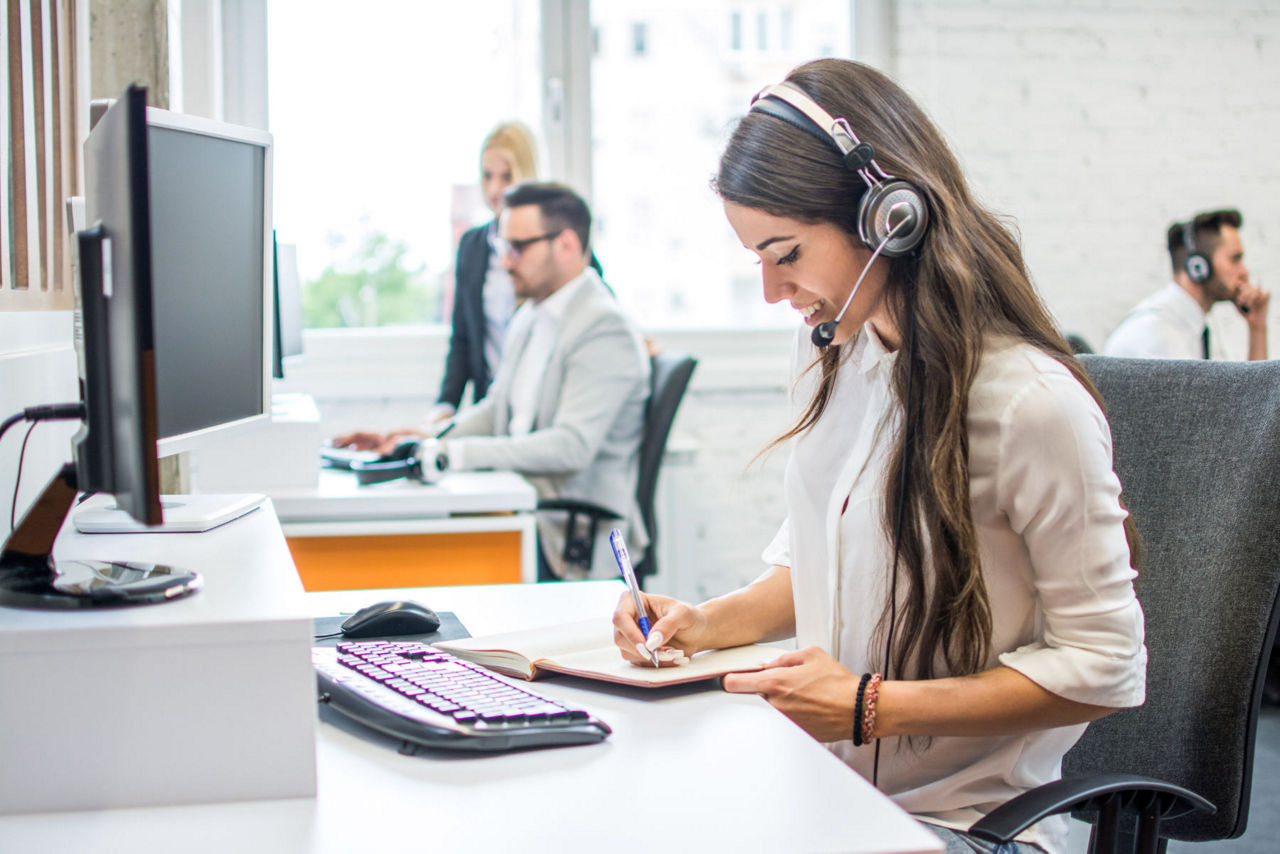 Vier Mtarbeiter sitzen auf Bürostühlen vor ihren Computern und telefonieren.