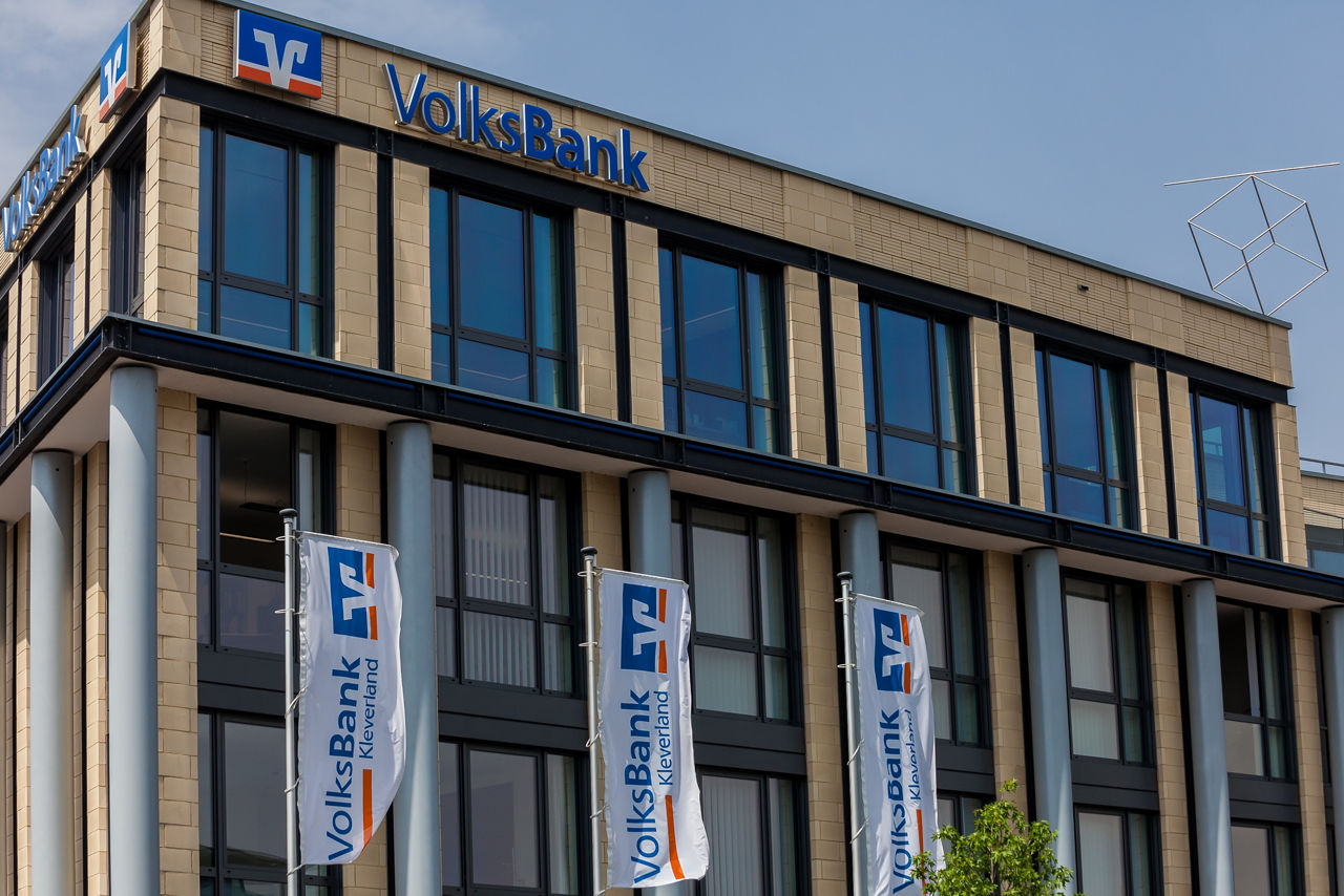 Drei Kinder einer Fußballmannschaft in Volksbank-Trikots freuen sich über ihren Erfolg.