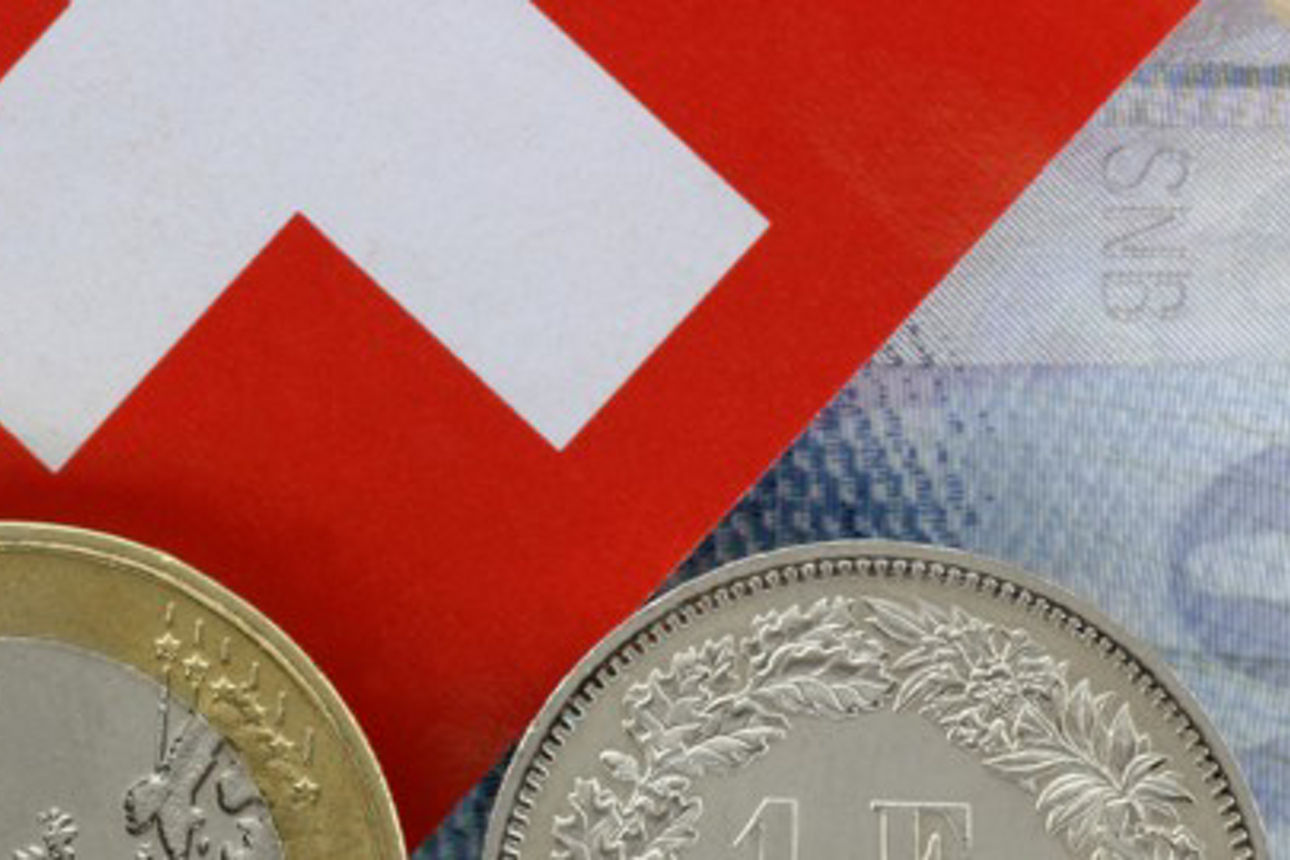 Schweizer Flagge liegt auf einem 100 Franken Schein. Darunter befindet sich eine 1-Euro-Münze und eine 1-Franken Mü