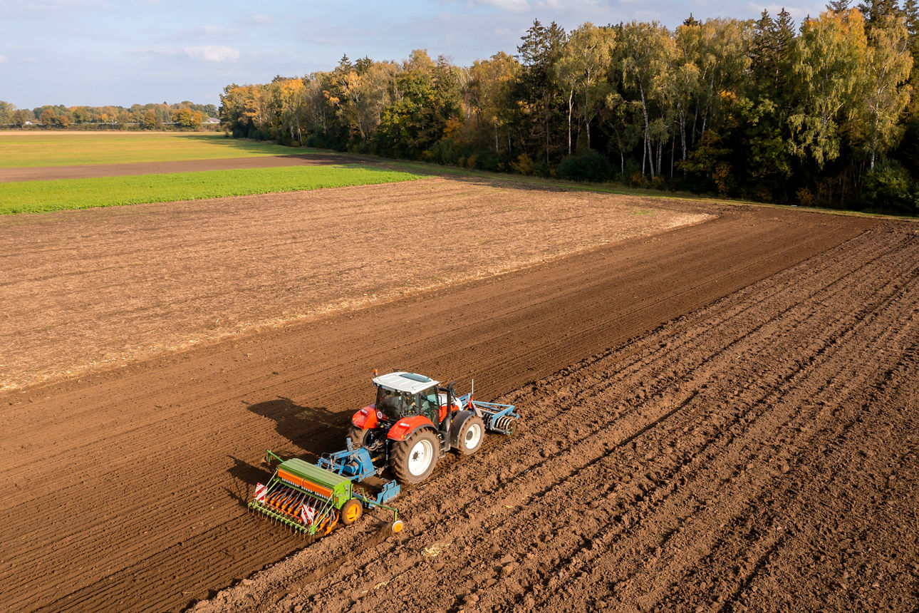 Ein roter Traktor pflügt ein Feld. Foto: Getty Images.