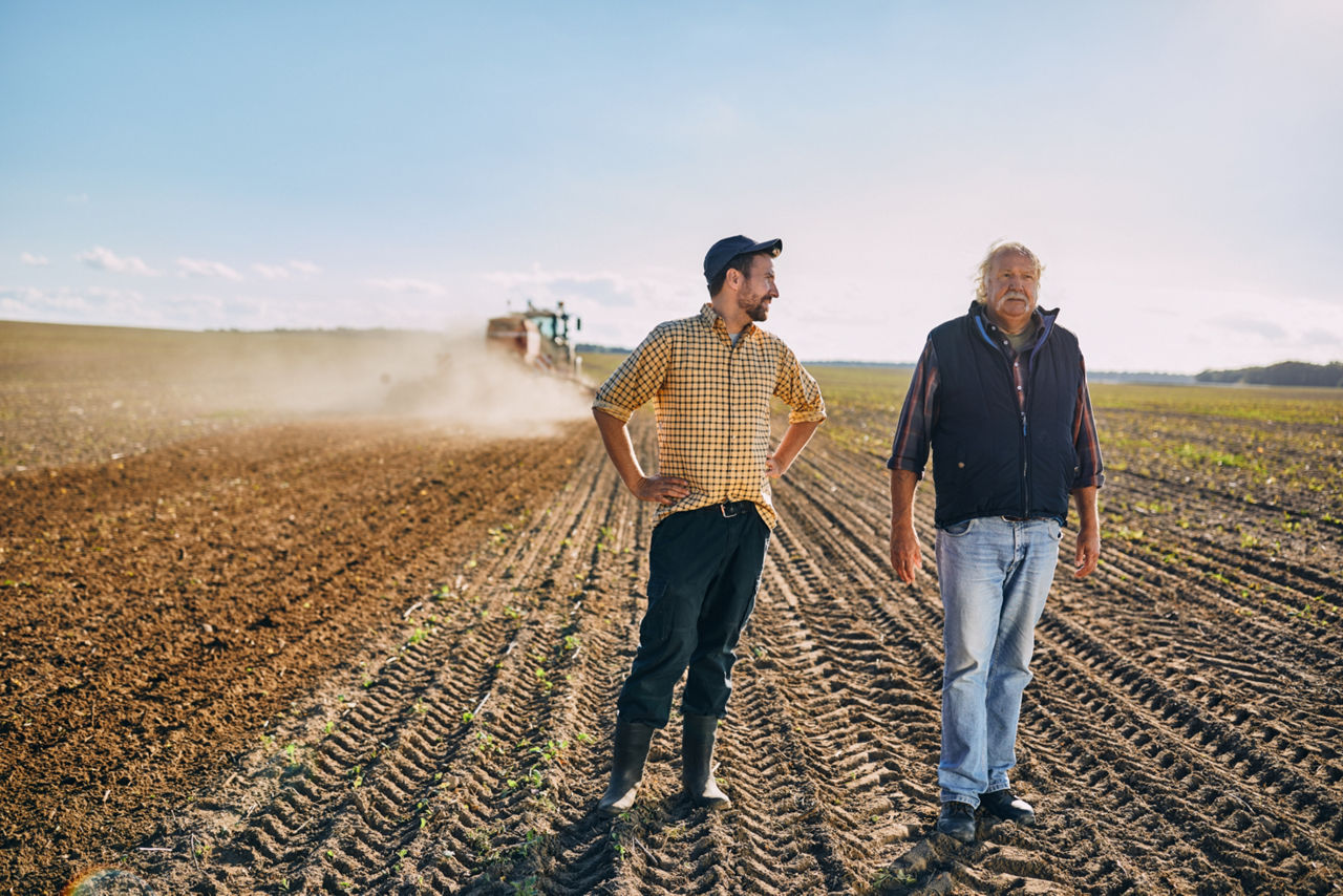 Ein Landwirt steht mit einem Mann auf einem Feld
