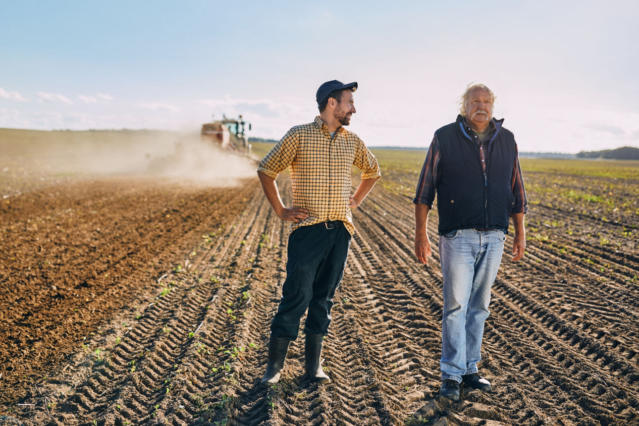 Ein Landwirt steht mit einem Mann auf einem Feld