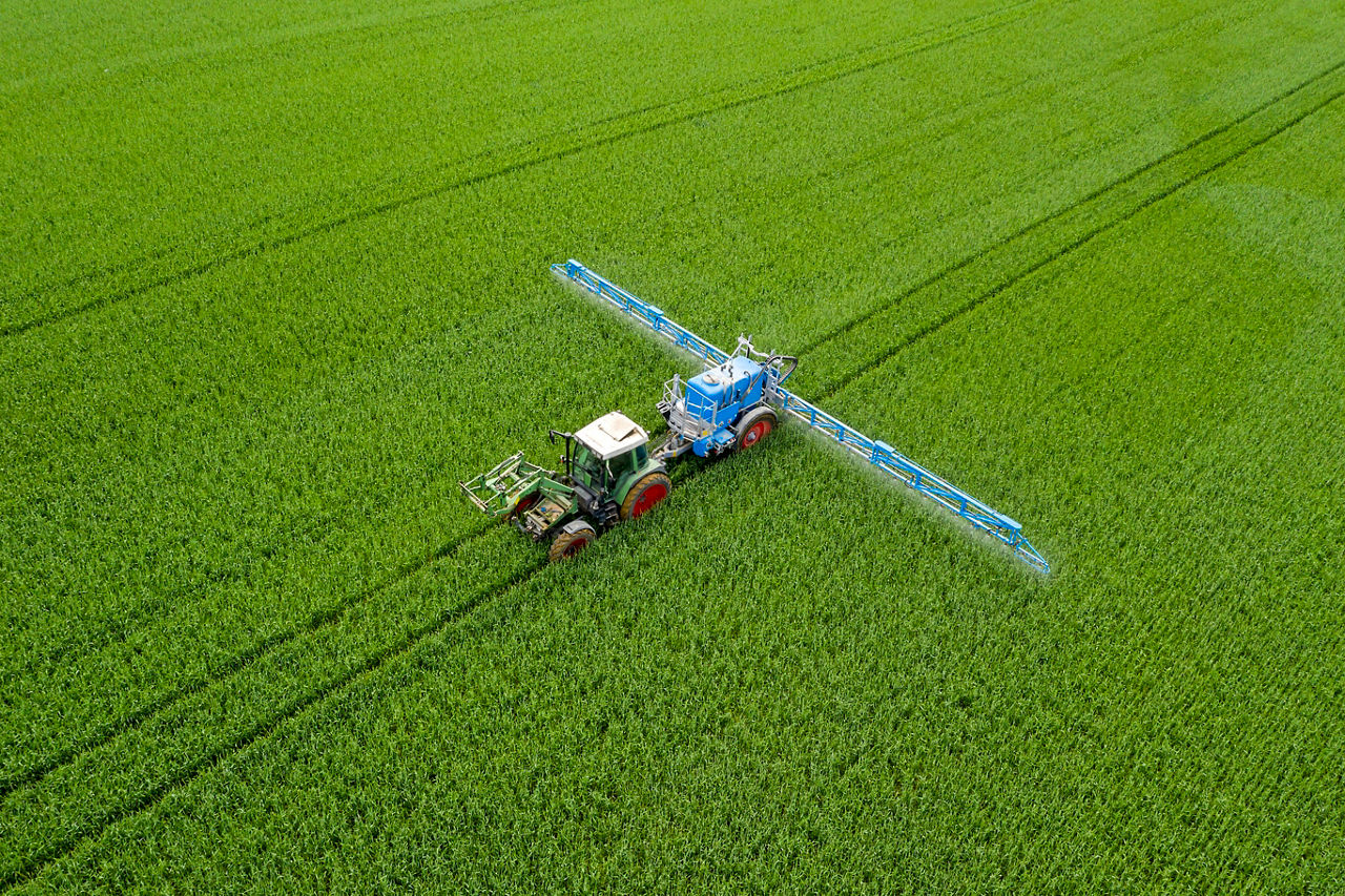 Ein Traktor fährt auf einem Feld und spritzt Pflanzenschutz. Foto: Getty Images 1248595508.