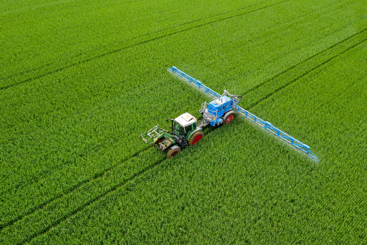 Luftaufnahme eines Landwirtschaftstraktors, der ein Weizenfeld besprüht. Foto: Getty Images.