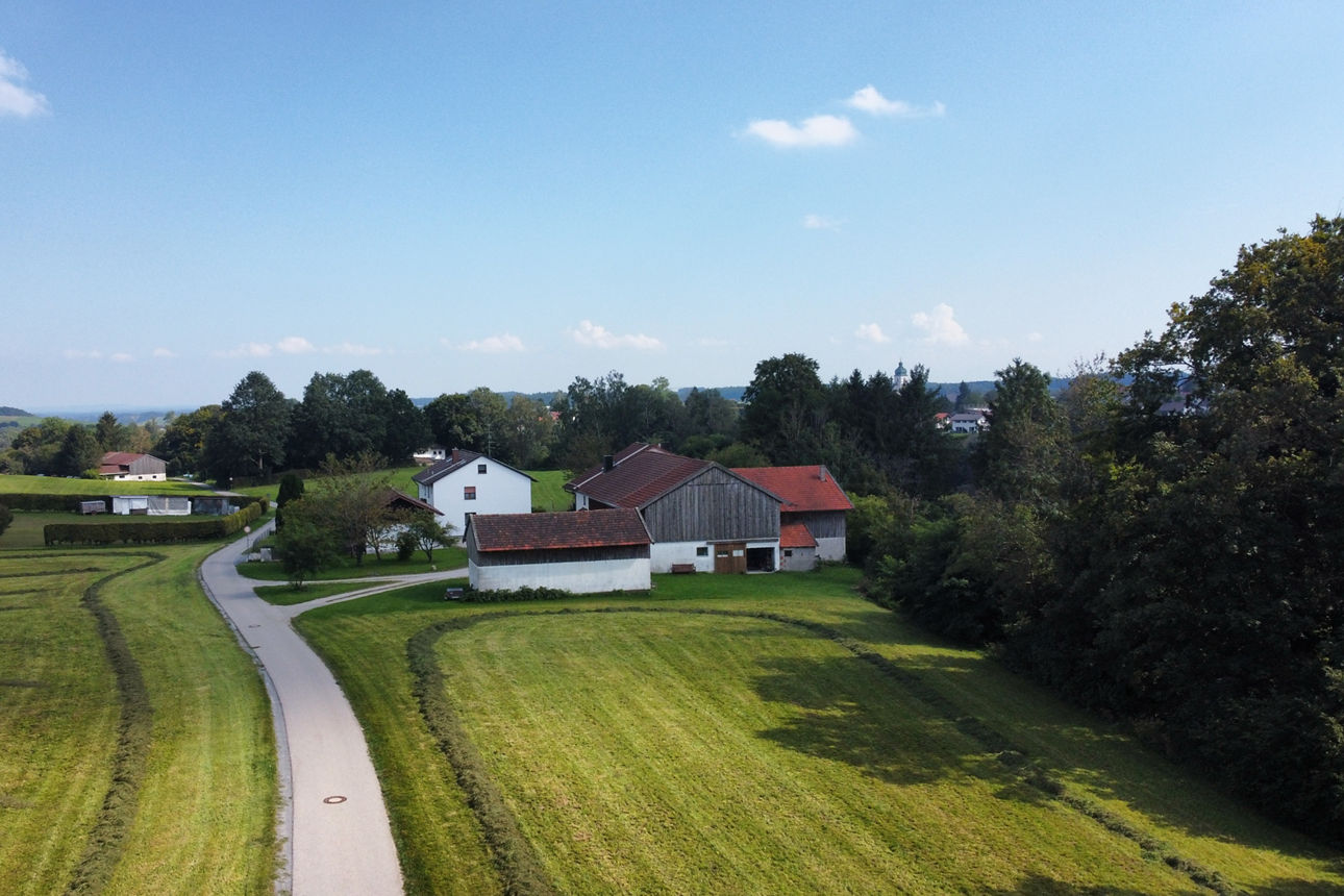 Malerische Aussicht auf einen Bauernhof mit Feldern und Straße unter blauem Himmel