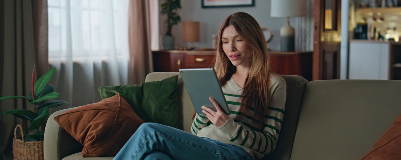 Junge Frau mit Tablet sitzt auf einer Couch