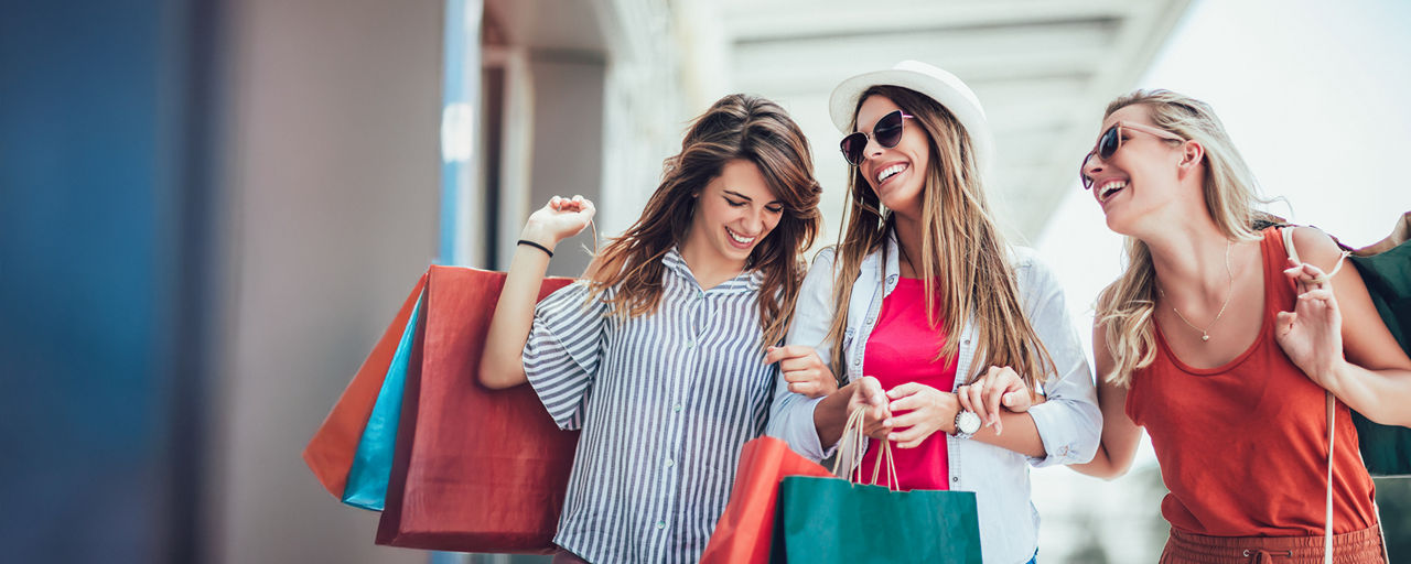 Drei lachende Frauen mit Shopping-Tüten 