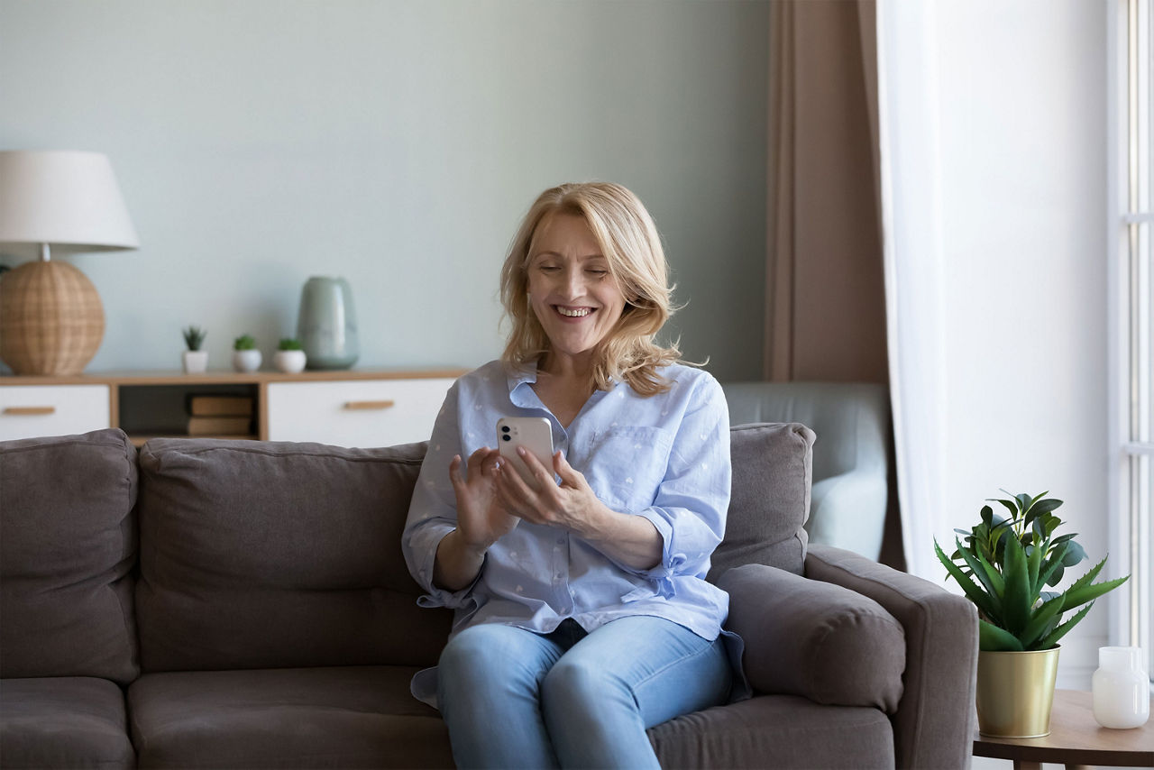 Frau sitzt auf dem Sofa und bedient ein Handy