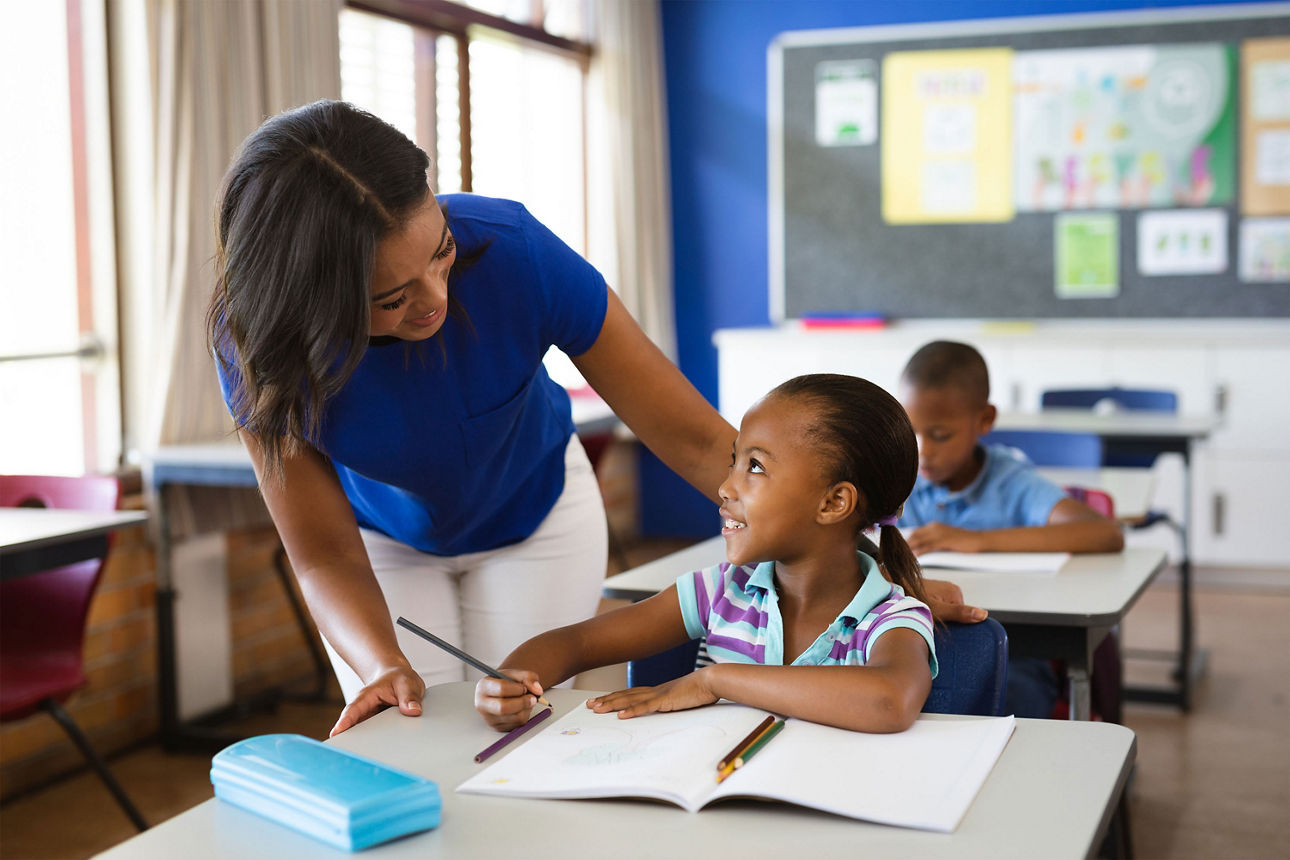 Afroamerikanische Lehrerin unterrichtet afroamerikanisches Mädchen in der Klasse an der Grundschule