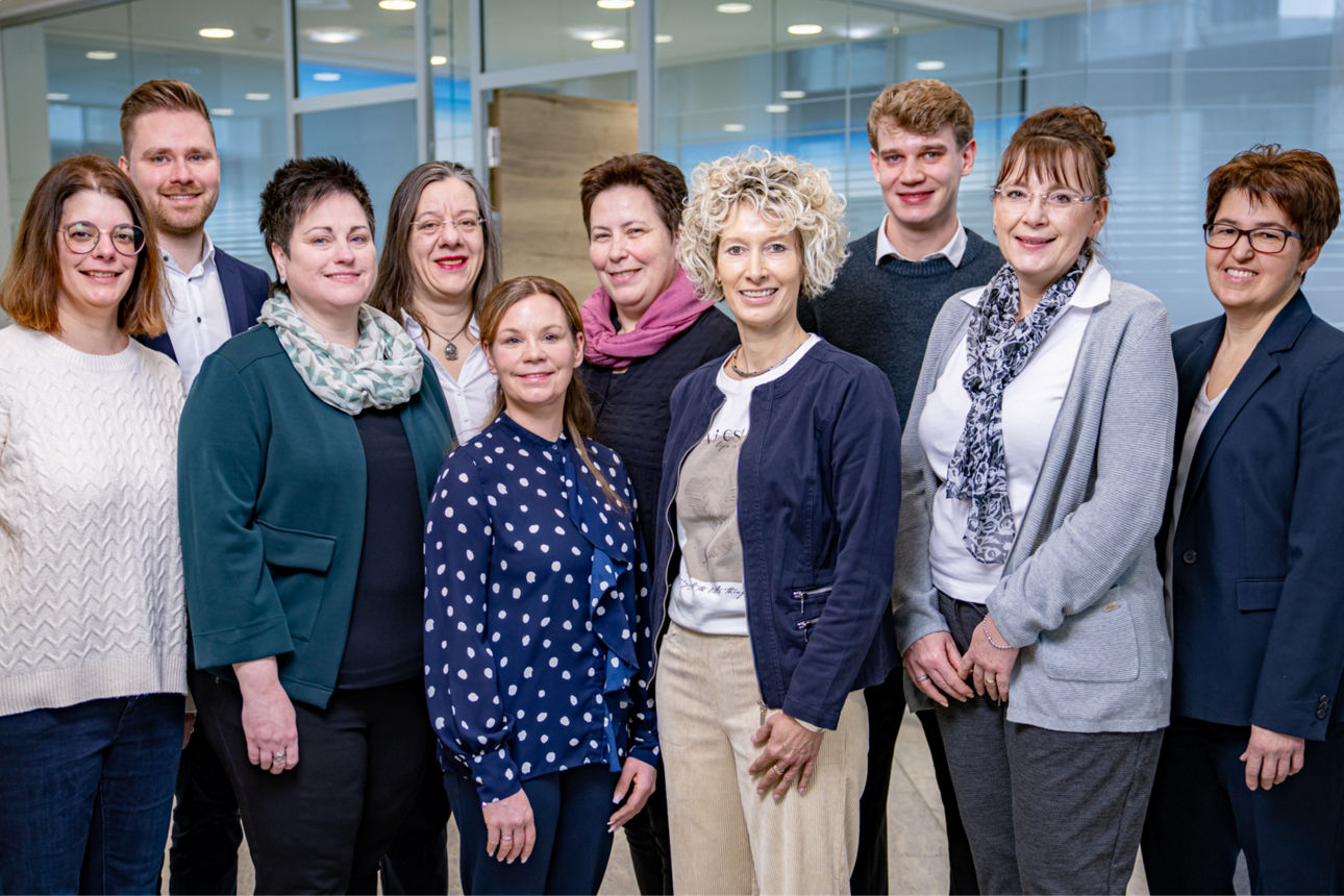 Eine Gruppe von Personen in typischer Bankkleidung steht vor einem Büro.