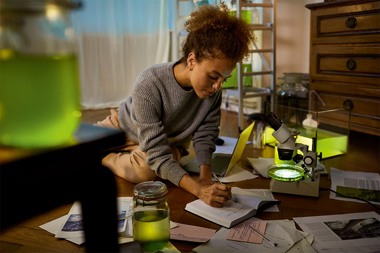 Frau sitzt auf ihrem Wohnzimmerboden umgeben von Unterlagen