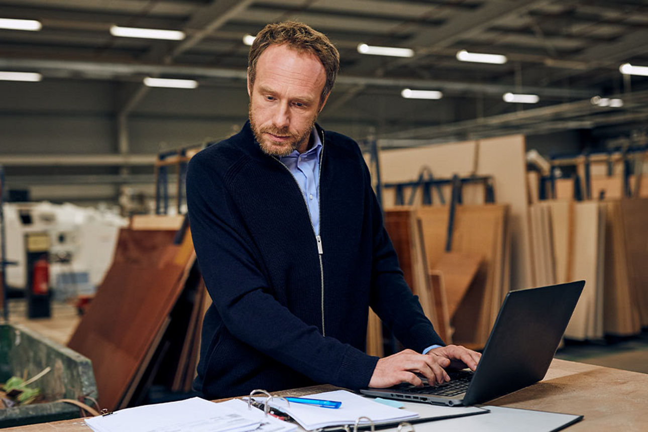 Ein Mann in einer Lagerhalle bei der Arbeit an einem Laptop