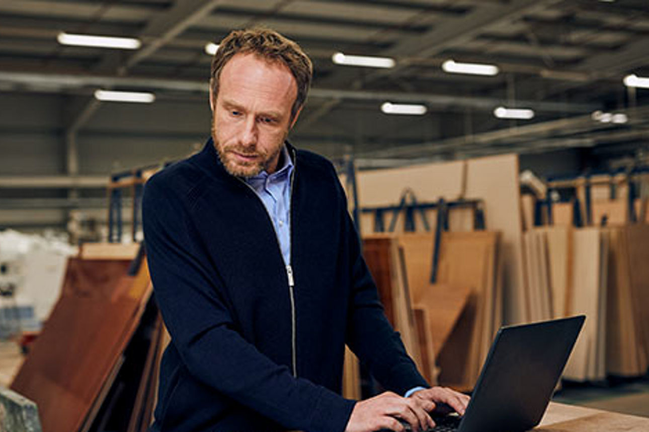 Ein Mann arbeitet in einer Werkstatt an einem Laptop