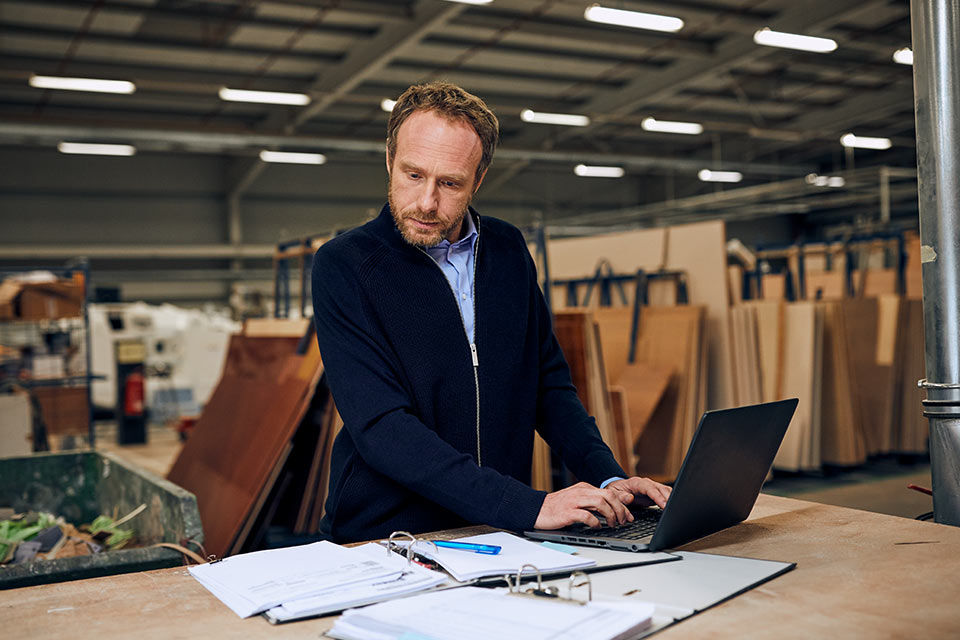 Ein Mann arbeitet in einer Werkstatt an einem Laptop