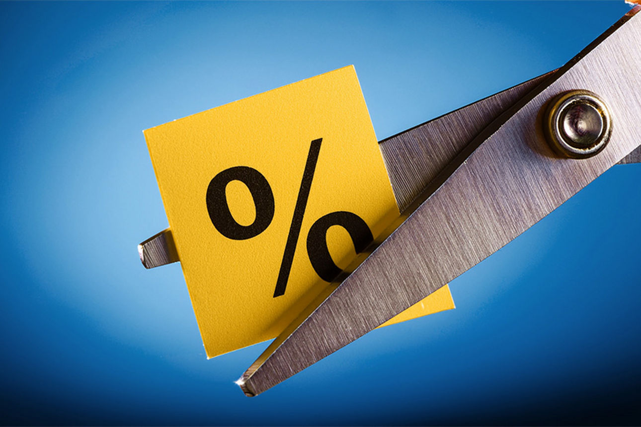 Eine Schere zerschneidet ein Post-It mit einem Prozentzeichen