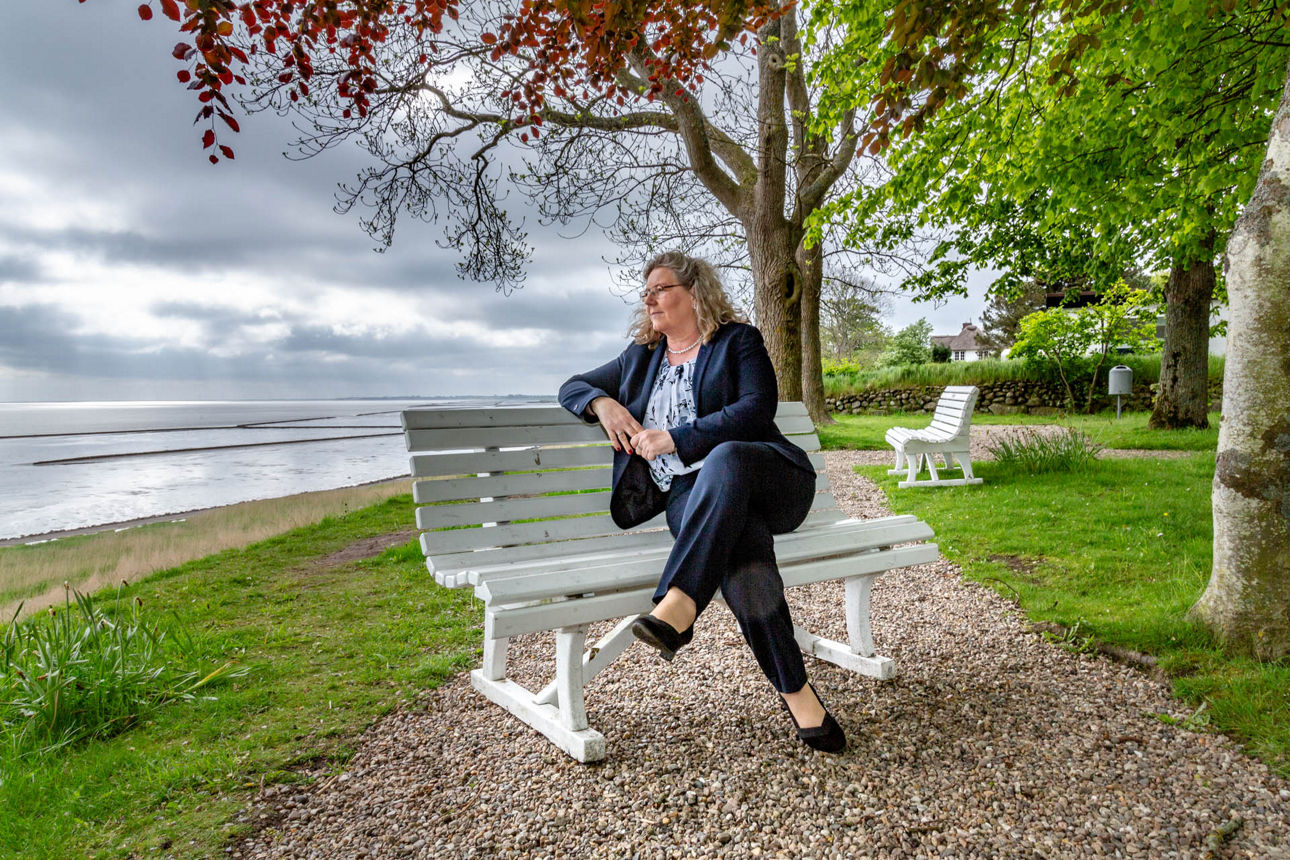 Eine Frau sitzt auf einer Bank am Wattenmeer