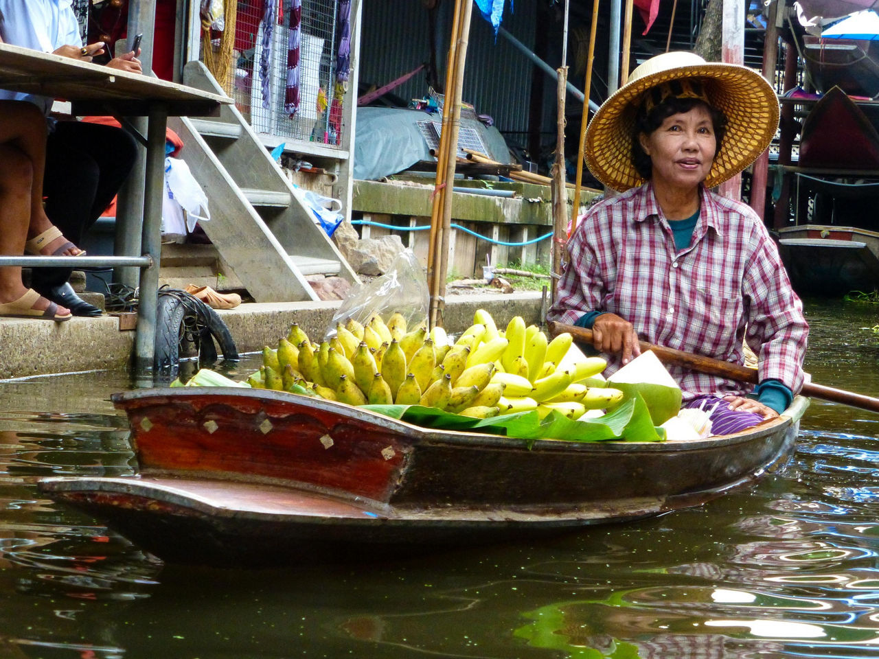 Eine Frau fährt mit einem kleinen Boot über einen Fluss und transportiert Bananen.