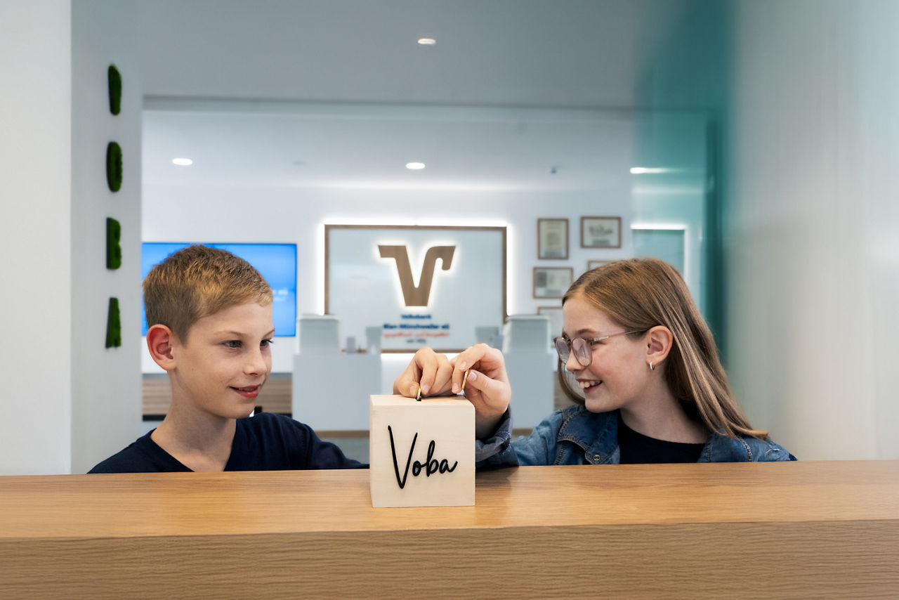 Kinder mit einer Spardose in einer Bankfiliale