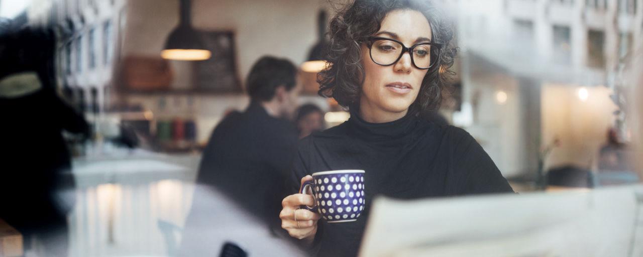 Weibliche Geschäftsfrau liest eine Zeitung im Café