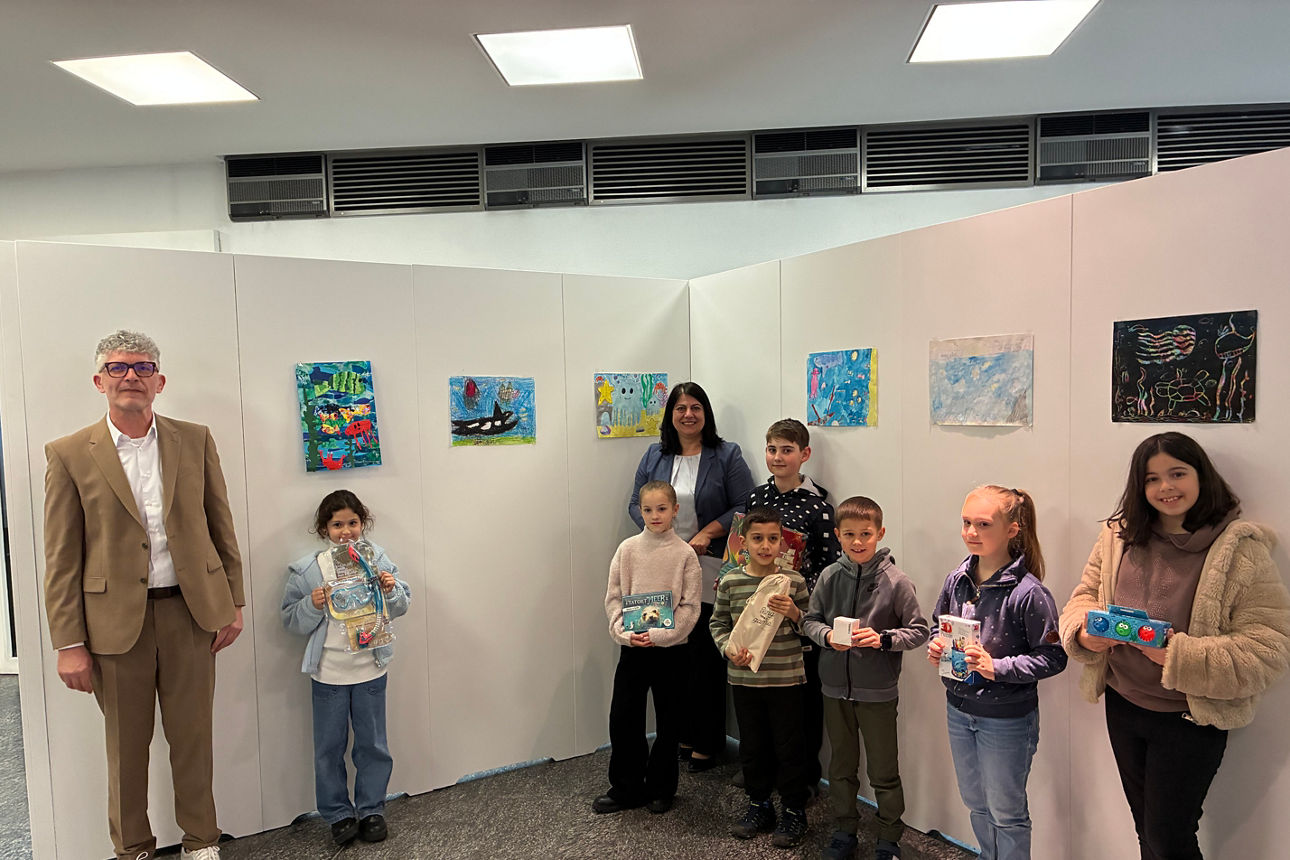 Kinder mit Ihren Bildern an einer Ausstellungswand. 