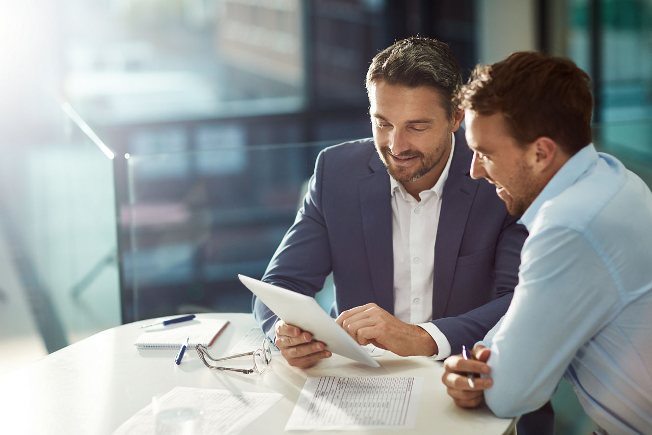 Zwei Business Männer sitzen in einem Meetingraum und sprechen über eine Haftpflichtversicherung für Manager eines Gewerbes